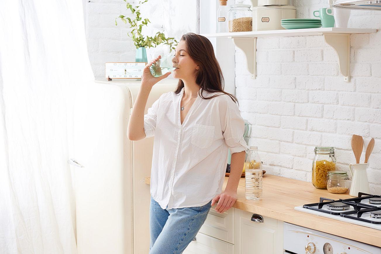 Frau trinkt in der Küche ein Glas Wasser